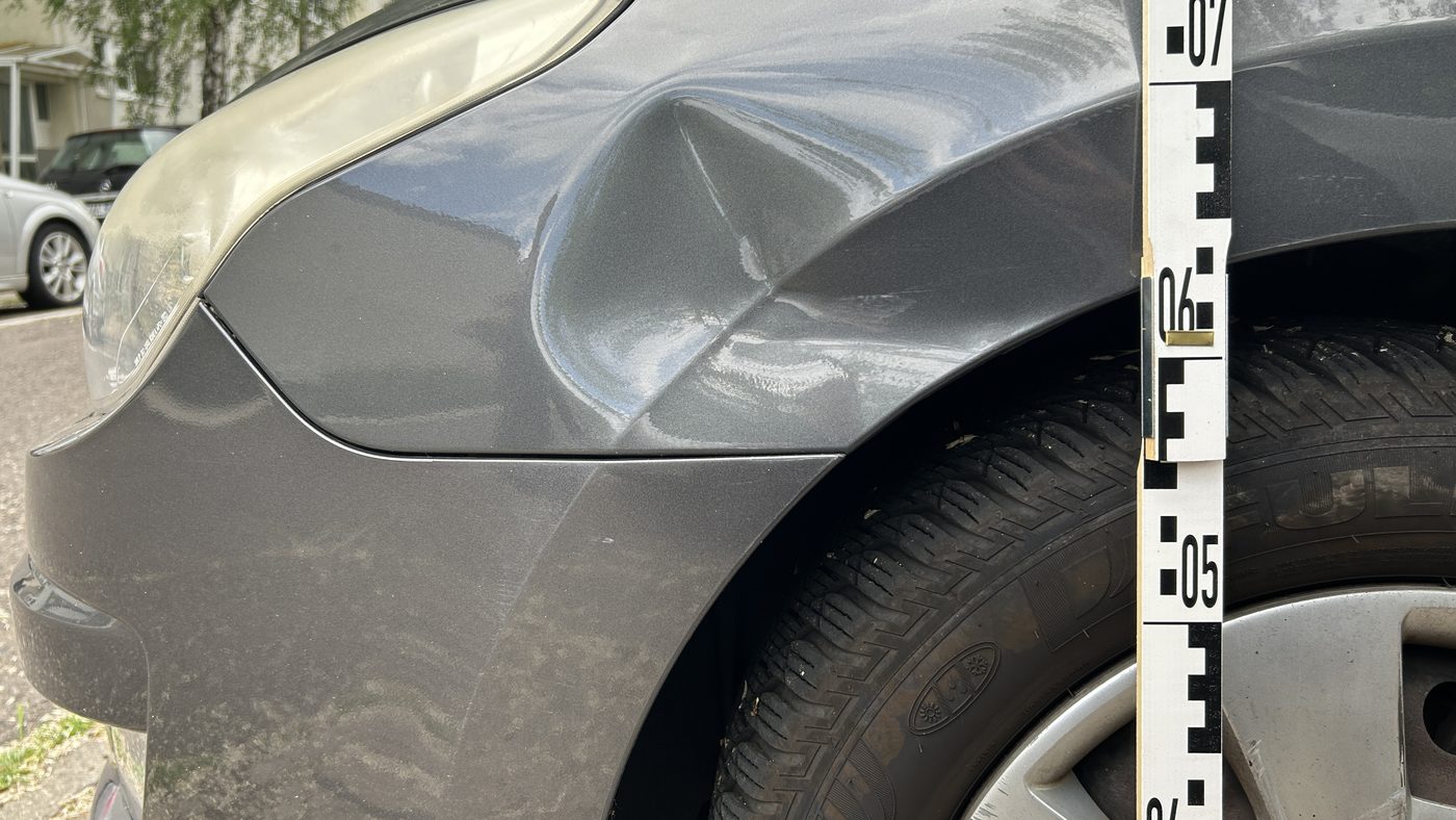 Verformter Kotflügel und beschädigte Stoßfängerverkleidung an einem Unfallfahrzeug